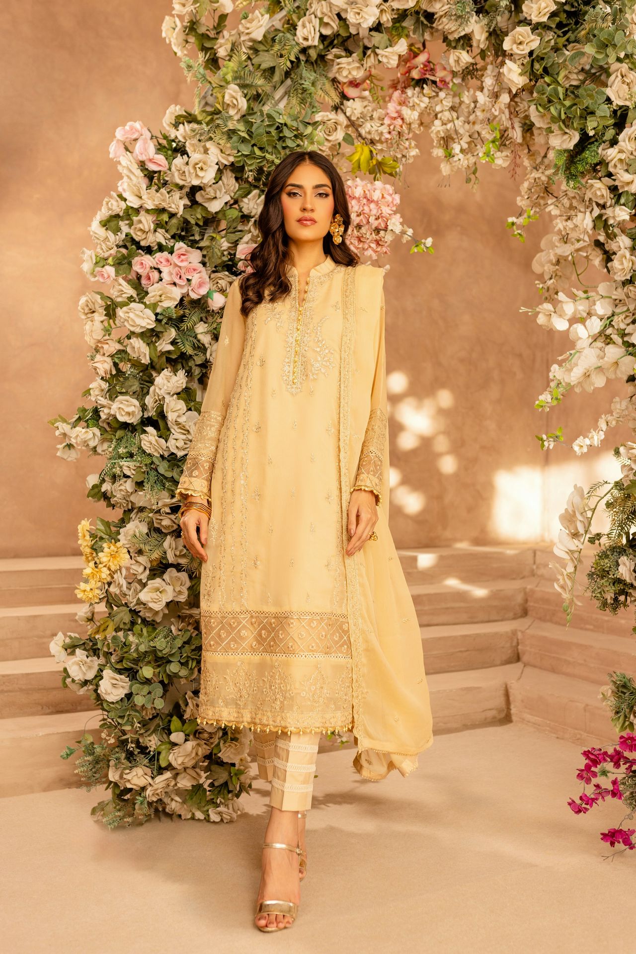 A woman standing in front of a floral arch